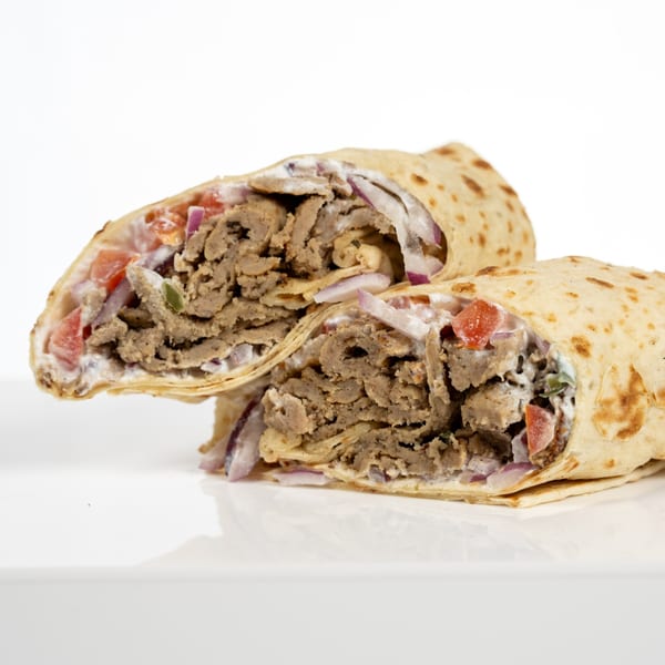 Two halves of a gyro wrap, filled with meat, tomatoes, red onions, and white sauce.