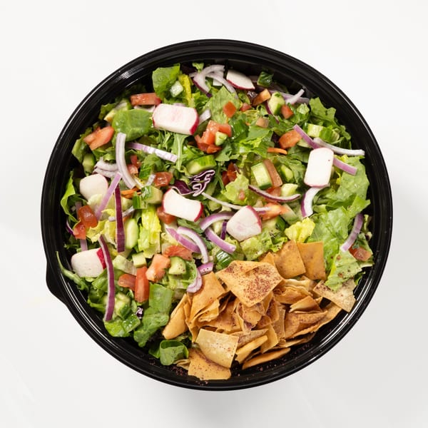 Overhead view of a fattoush salad with lettuce, tomatoes, cucumbers, radishes, red onions, and pita chips.